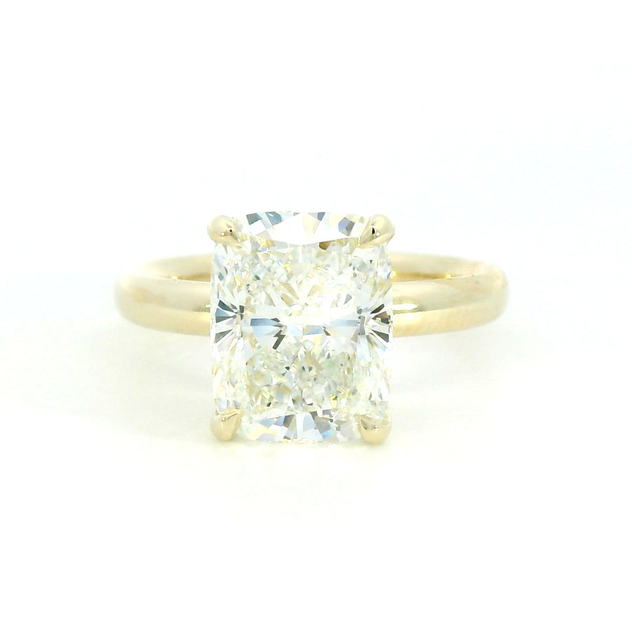A close-up image of a gold ring with a smooth, polished finish, featuring a single round diamond set in the center. The ring is displayed against a plain white background.