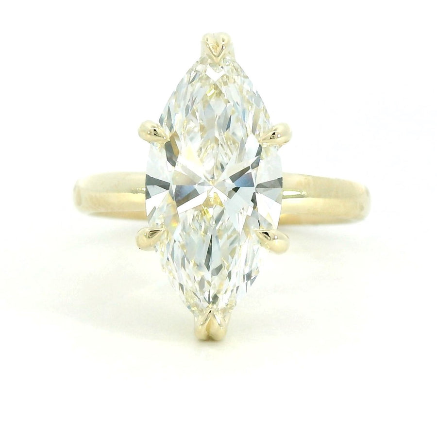 A close-up image of a gold ring with a smooth, polished finish, featuring a single round diamond set in the center. The ring is displayed against a plain white background.