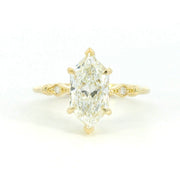 A close-up image of a gold ring with a smooth, polished finish, featuring a unique, modern design with a slightly twisted band, displayed on a neutral background.