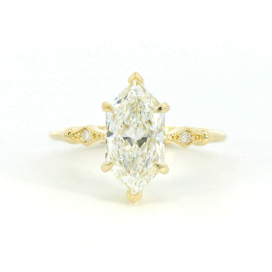 A close-up image of a gold ring with a smooth, polished finish, featuring a unique, modern design with a slightly twisted band, displayed on a neutral background.