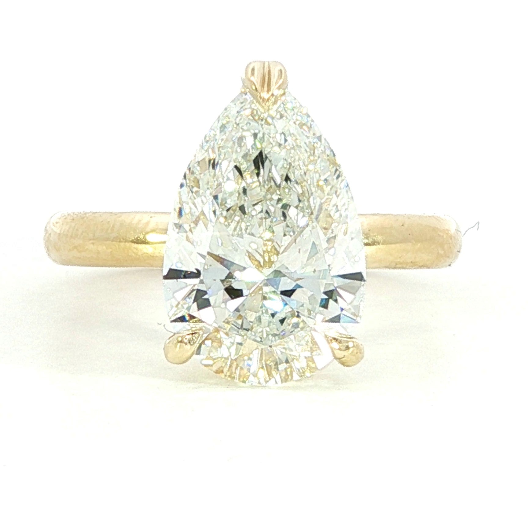 A close-up photo of a gold ring with a rectangular, clear gemstone set in the center, displayed on a white background. The ring features a simple, elegant band and a modern, minimalist design.