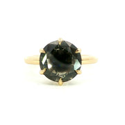 A close-up image of a gold ring with a smooth, polished finish, featuring a single round diamond set in the center. The ring is displayed against a plain white background.