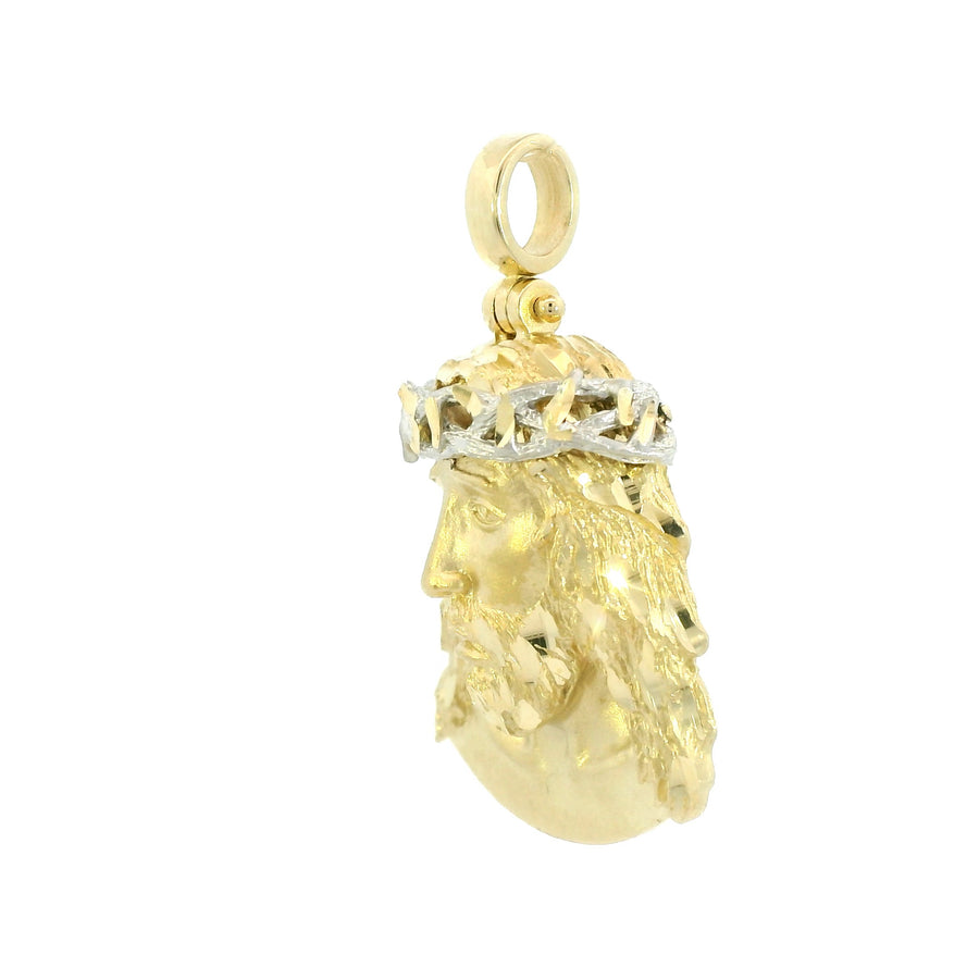 Gold pendant with a face design on a white background