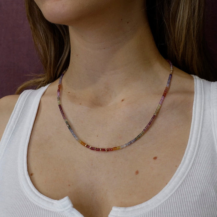 Close-up of a woman wearing a colorful beaded necklace with a white tank top.