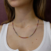 Close-up of a person wearing a beaded necklace with a white top.