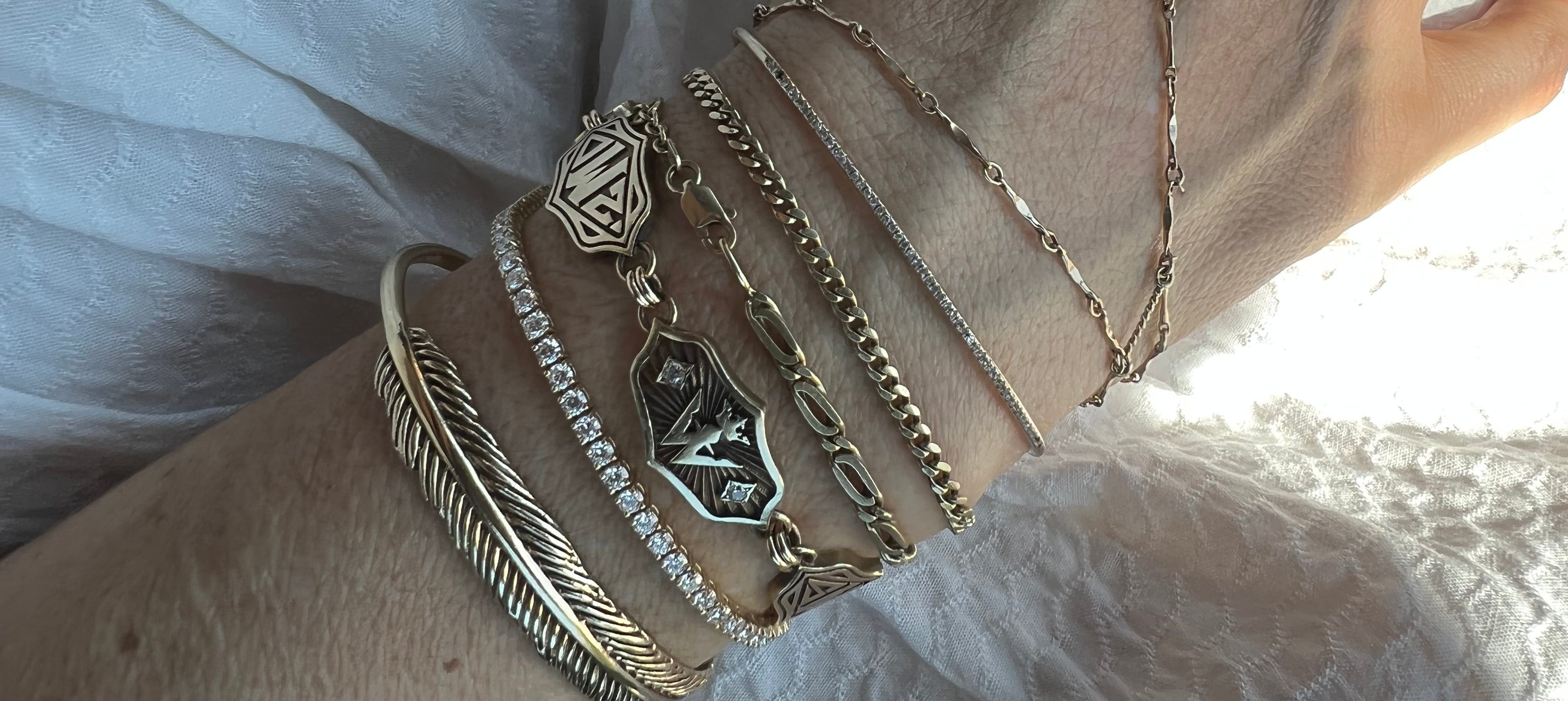 Close-up of a wrist wearing multiple gold bracelets on a light background