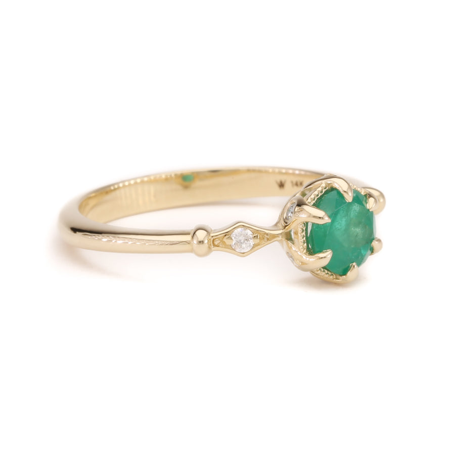 A delicate 14K solid yellow gold ring featuring a vibrant green emerald centerpiece in a fairytale-inspired setting, photographed from the side to showcase its elegant band and intricate design details.