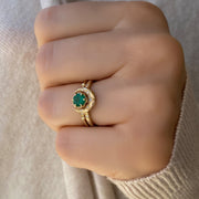 A close-up image of two elegant 14kt solid gold rings: one features a round emerald gemstone in a classic setting, and the other is a crescent horn-shaped band. Both rings are displayed side by side on a neutral background, highlighting their fine craftsmanship and vibrant green gemstone.